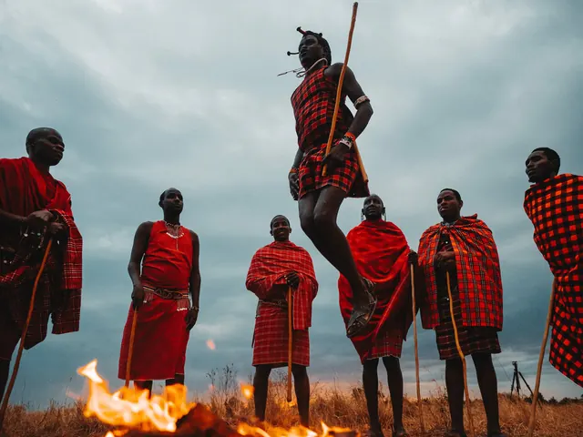 Maasai men leap and gather around a campfire at dusk in Kenya